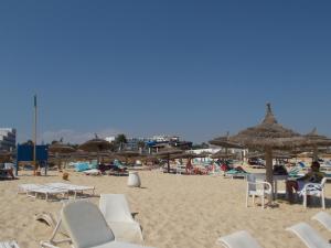 a sandy beach with chairs and umbrellas on it at Douja Apartment in Nabeul