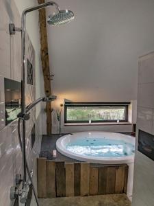 uma banheira de hidromassagem numa casa de banho com janela em Les Hauts de Bagadou em Martel