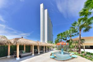 北芭堤雅的住宿－Centre Point Prime Hotel Pattaya，一个带游泳池和稻草遮阳伞的度假村和一座建筑