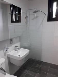 a white bathroom with a sink and a shower at Sogobe Jeju House in Jeju