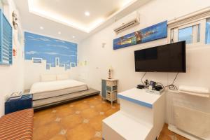 a room with a bed and a flat screen tv at Rococo Homestay in Hengchun