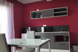 a dining room with a table and a red wall at Enonatja Studio - 5min des plages et du centre de St Pierre in Saint-Pierre