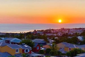 a sunset over a city with houses and the ocean at Enonatja Studio - 5min des plages et du centre de St Pierre in Saint-Pierre