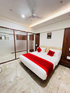 1 dormitorio con 1 cama grande con almohadas rojas en LEELA BIZOTEL en Jūnāgadh