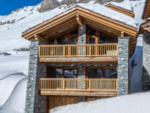 a log cabin with a deck in the snow at Chalet de luxe avec piscine, sauna, hammam, cinéma et salle de jeu - FR-1-694-3 in Val dʼIsère