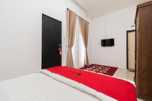 a bedroom with a large bed with a red blanket at RedDoorz Syariah at Jalan Andalas Padang in Kampungdurian