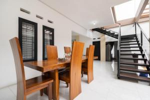 a dining room with a wooden table and chairs and a staircase at RedDoorz Syariah at Jalan Andalas Padang in Kampungdurian