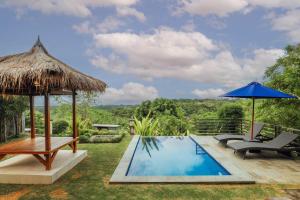 a pool with two chairs and a umbrella at BB Resort Villa and Spa in Nusa Penida
