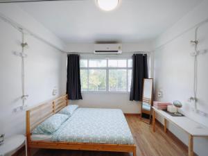 a bedroom with a bed and a desk and a window at Room Story Hostel in Phra Nakhon Si Ayutthaya