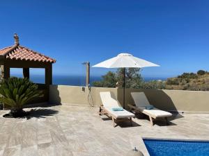 patio z 2 krzesłami i parasolem w obiekcie El Sentimiento Don Javier Apartment w mieście Torrox