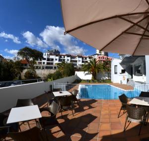 a patio with tables and chairs and a swimming pool at Madeira Bright Star by Petit Hotels in Funchal