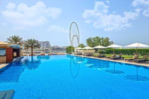 a large swimming pool with a ferris wheel in the background at Al Bateen · Ultra Luxury JBR · Private Beach and Pool in Dubai