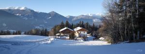 a house in the snow with mountains in the background at Residence Alpenrose in Bressanone