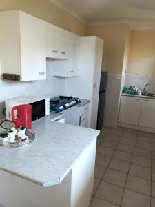 Una cocina con gabinetes blancos y encimera. en 15 on 11th Summerstrand, en Summerstrand