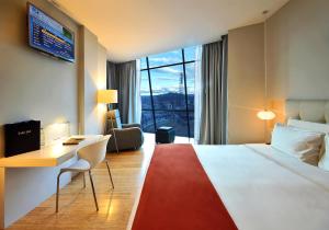 a hotel room with a bed and a desk and a window at TRYP by Wyndham Cuenca Zahir in Cuenca