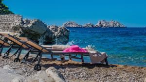a bench on a beach next to the water at Hotel Splendid in Dubrovnik