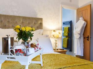 a bed with a table with a vase of flowers on it at Thistle Cottage - Uk30523 in Staintondale