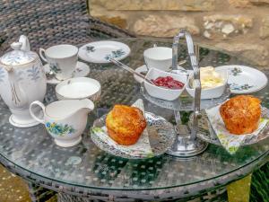 a glass table with food and cups and muffins on it at Thistle Cottage - Uk30523 in Staintondale