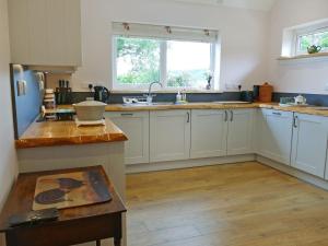 a kitchen with white cabinets and a wooden floor at Easter Lettoch in Advie
