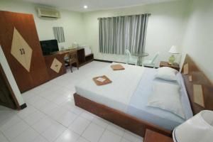 ein Hotelzimmer mit einem großen Bett und einem Schreibtisch in der Unterkunft Green Island Guesthouse in Karon Beach