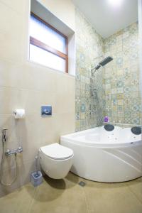 een badkamer met een bad, een toilet en een wastafel bij Nino's Cosy Apartment in Koetaisi
