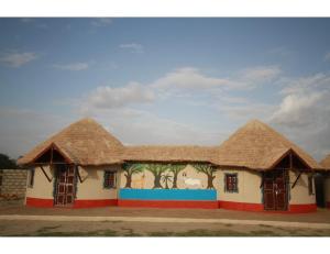 Rann Chandni Resort, Kutch, Bhuj في Bherandiāla: مبنى بسقف من القش وعليه لوحة