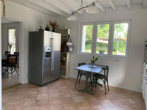 a kitchen with a refrigerator and a table at Bâtisse en pierre XVII siècle 115 M² avec terrasse in Ambarès-et-Lagrave