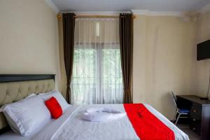 マカレにあるRedDoorz at Makale Tana Torajaのベッド(赤と白の枕付)、窓が備わります。