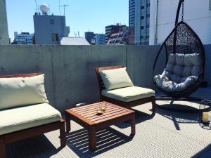 une terrasse avec 2 chaises, une balançoire et une table dans l'établissement Ken's Place四谷, à Tokyo