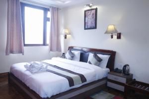 una camera da letto con un letto con lenzuola bianche e una finestra di Hotel De Villa Gangtok a Gangtok