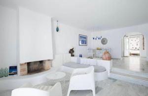 a living room with white furniture and a fireplace at Villa Maestro Mykonos in Agios Ioannis Mykonos