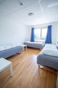 um quarto com duas camas e uma janela com cortinas azuis em Kristiansand Feriesenter em Kristiansand