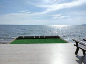 una vista del océano con un banco junto al agua en Talaytime Pool Villa en Laem Sing