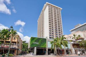 a tall building on a street with palm trees at OUTRIGGER Waikiki Beachcomber Hotel in Honolulu