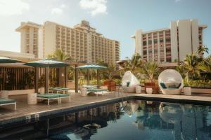 a beach with a pool, chairs, tables and umbrellas at Waikiki Beachcomber by Outrigger in Honolulu