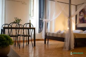 a bedroom with a bed and a table and chairs at Ostia Holiday Naxos in Lido di Ostia +3 photos