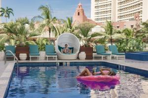 OUTRIGGER Waikiki Beachcomber Hotel في هونولولو: وضع المرأة على لوحة إعلانية في حمام السباحة