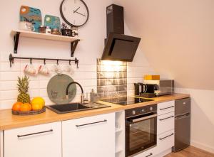 a kitchen with white cabinets and a clock on the wall at Dluga 66 Attic in Gdańsk