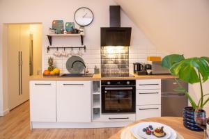 a kitchen with white cabinets and a clock on the wall at Dluga 66 Attic in Gdańsk