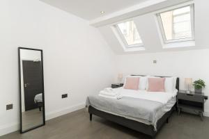 a white bedroom with a bed and a mirror at Oxford Street 2 Bedr, 3 Beds, 2,5 Bath, 2 min subway in London