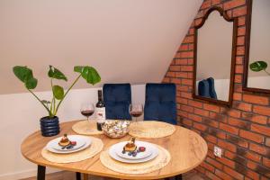 a wooden table with two plates of food and wine glasses at Dluga 66 Attic in Gdańsk