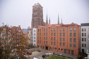 a large brick building with a clock tower in a city at Dluga 66 Attic in Gdańsk