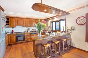 a kitchen with wooden cabinets and a large island with bar stools at Casa La Victoria in La Victoria de Acentejo +20 photos