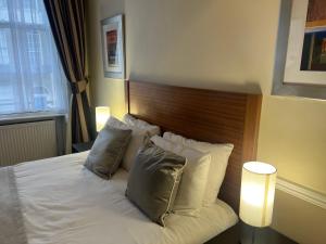 a bedroom with a white bed with a wooden headboard at Hotel Cavendish in London