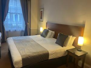 ein großes Bett in einem Hotelzimmer mit zwei Lampen in der Unterkunft Hotel Cavendish in London
