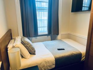 a small bedroom with a bed with a window at Hotel Cavendish - Bloomsbury in London