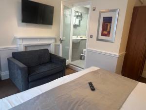 a room with a bed and a chair and a television at Hotel Cavendish - Bloomsbury in London