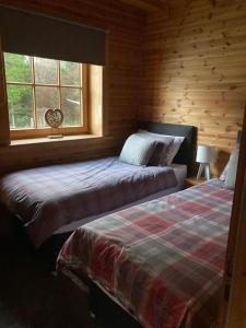 a bedroom with two beds in a log cabin at Norwegian Log Cabin The Roe Deer -sauna & hot tub in Keith