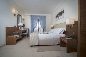 Habitación de hotel con cama, escritorio y ventana en Suites & Residence Hotel, en Pozzuoli