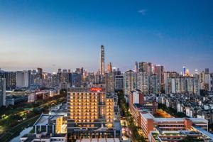 eine Skyline der Stadt mit einem hohen Gebäude im Vordergrund in der Unterkunft Hampton By Hilton Shenzhen Futian Mangrove Park Apartments in Shenzhen
